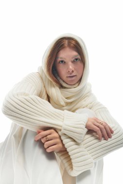 Genç bir kızıl zarif poz veriyor, rahat bir kazak giyiyor, kış modasını gözler önüne seriyor..