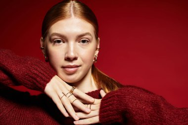 Kızıl saçlı kadın zarif bir şekilde örgü örüyor, ışık saçan bir tarzı ve sıcaklığı var..