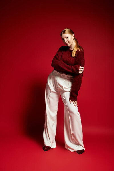 A young woman with red hair poses confidently in a stylish winter sweater.