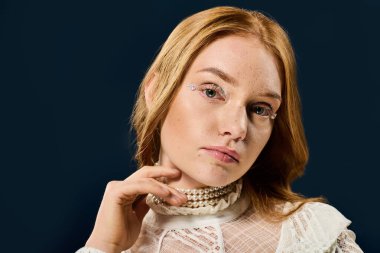 Genç ve güzel bir kadın, özünü koyu bir arkaplanda düşünceli bir ifadeyle sergiliyor..