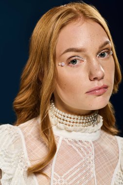 Çekici genç bir kadın zarif poz verir, koyu bir arkaplanda inci aksanıyla süslenir..