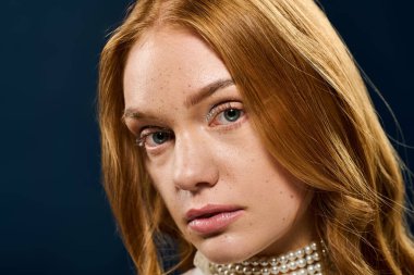 Kızıl saçlı ve çilli genç bir kadın düşünceli bir şekilde bakıyor, doğal güzelliğini gösteriyor..