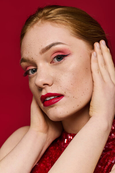 A beautiful young woman showcases her makeup artistry and vibrant style in a studio setting.