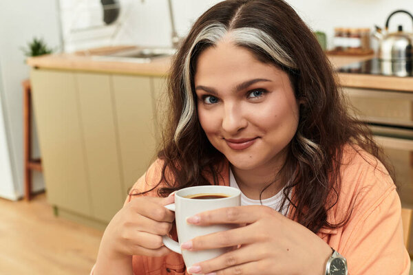 A woman with a striking white forelock relaxes at home while sipping coffee.