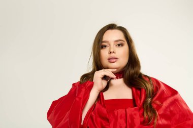 Geniş cüsseli genç bir kadın canlı kırmızı bir elbiseyle kış kutlamalarına sevinçle sarılır..