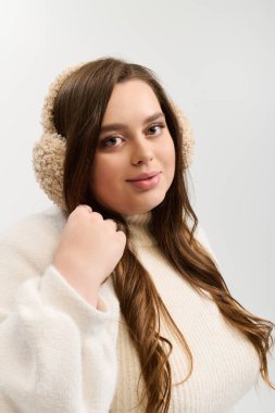 Parlak stüdyo, kalın beden bir genç kadının kalın örgü bir süveter giydiğini gösteriyor..