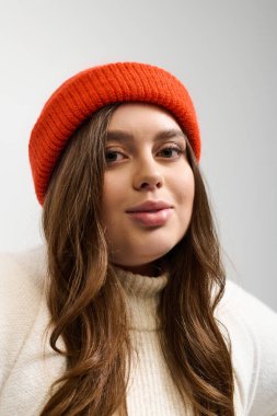 Genç bir kadın sıcak, örülü bir süveterin içinde rahat bir atmosfer yaratarak rahatça poz verir..