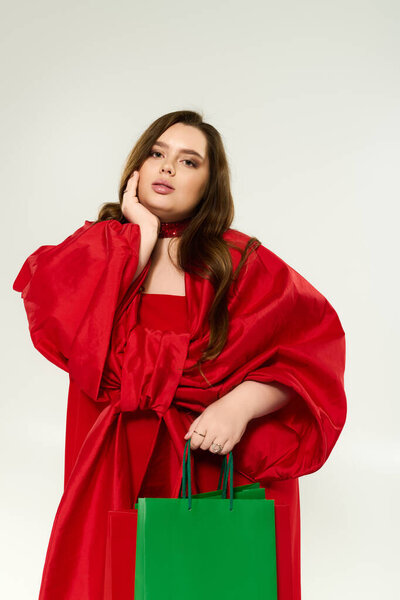 A plus size young woman in a stunning red outfit with a bow enjoys the holiday spirit.