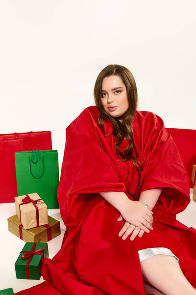 Плюс размер молодая женщина наслаждается праздничный дух, в окружении рождественских подарков и развеселить.