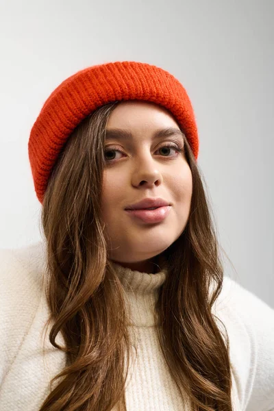 Genç bir kadın sıcak, örülü bir süveterin içinde rahat bir atmosfer yaratarak rahatça poz verir..