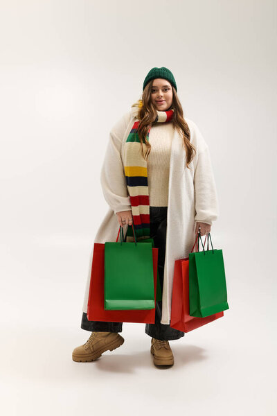 Молодая женщина, одетая тепло, наслаждается праздничным сезоном в окружении праздничных подарков зимой.