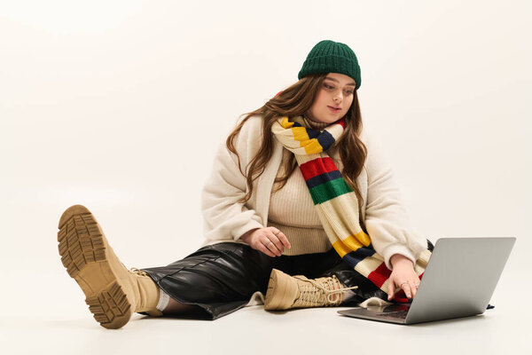 Молодая женщина наслаждается своим уютным вязаным свитером во время работы на ноутбуке.