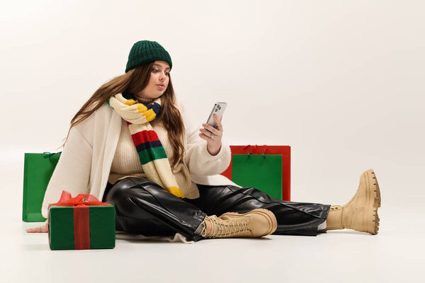 Молодая женщина plus size наслаждается праздничным духом в окружении праздничных рождественских подарков.