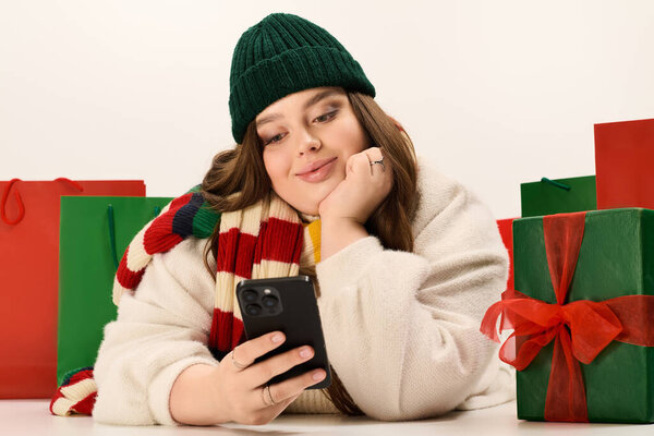Молодая женщина в уютной зимней одежде наслаждается праздничным моментом в окружении красочных рождественских подарков.