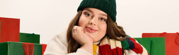 Молодая женщина в зимнем снаряжении наслаждаясь праздничным духом с красочными рождественскими подарками, баннер