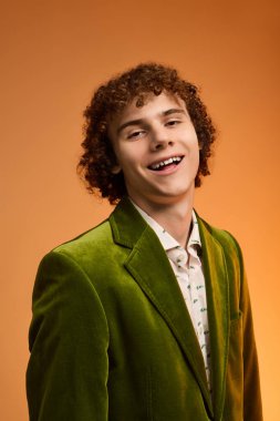 Kıvırcık bir çocuk şık yeşil kadife bir ceket giyer ve stüdyoda gülümser..
