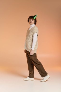 Örgülü yelek giymiş neşeli bir genç çocuk doğum günü kutlamaları için festival stüdyosunda poz veriyor..