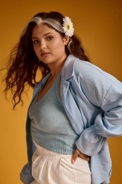 Genç bir kadın kendine güvenerek bir stüdyoda poz veriyor, güzelliğini ve ayırt edici özelliklerini sergiliyor..