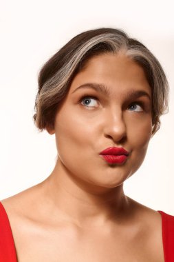 Genç bir kadın gururla canlı kırmızı dudaklarını ve çarpıcı beyaz perçemini gösterir..