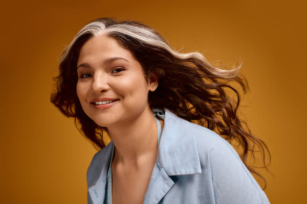 In a bright studio, a young woman embraces her unique appearance with confidence and joy.