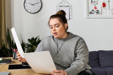 Güzel, iri yarı bir kadın şık bir ev masasında otururken yaratıcı projesine odaklanır..