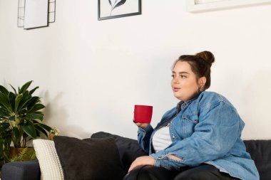 Güzel, iri yarı bir kadın kanepede rahatlar, rahat bir yerde içkisinin tadını çıkarır..