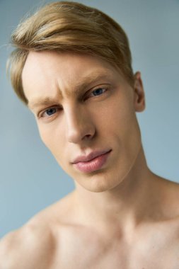 Çekici özellikleri olan yakışıklı genç bir adam modern erkekliği kucaklarken kendinden emin bir şekilde bakıyor..