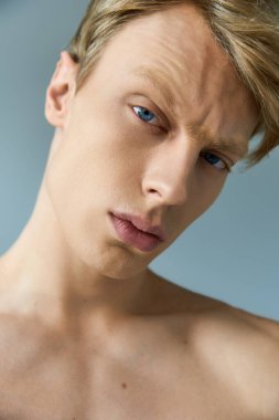 Yakışıklı genç bir adam, modern erkeksi estetik sergileyen izleyiciye özgüvenle bakıyor..