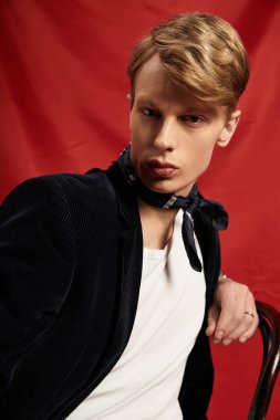 Genç, yakışıklı bir adam cesur, kırmızı bir arka plana güvenle poz veriyor, modern tarzı sergiliyor..