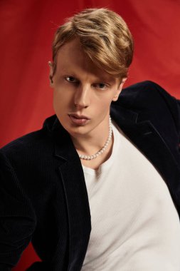 Çekici genç bir adam çarpıcı bir arka plana karşı güven yayar, modern erkekliği somutlaştırır..