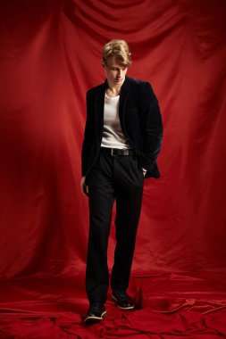 Genç bir adam modern erkeksiliği, cazibesini ve zarafetini cesur bir arkaplanda sergiliyor..