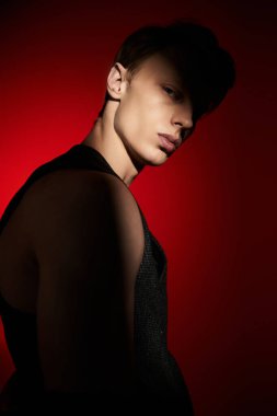 Genç bir adam kendine güvenerek ayakta duruyor. Tarzını gözler önüne seren çarpıcı ışıkla vurgulanıyor..