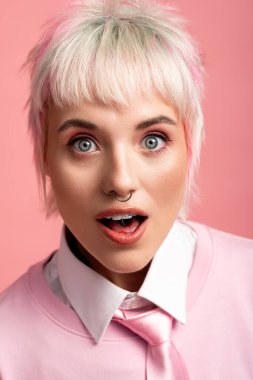 Çarpıcı özellikleri olan genç bir kadın pembe bir arka planda harikalar yaratıyor..