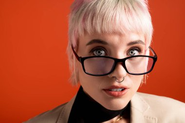 Genç bir kadın kendine güvenerek poz veriyor, çarpıcı özelliklerini ve canlı stilini vurguluyor..