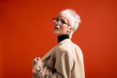 Kendine güvenen genç bir kadın modaya uygun kıyafetleri ve gözlükleriyle eşsiz tarzını sergiliyor..