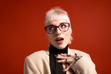 Sevimli genç bir kadın, parlak kırmızı bir arkaplanda büyüleyici bir şekilde poz verir..