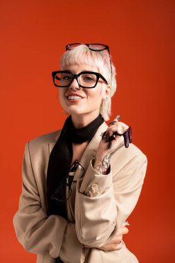 Çekici genç kadın kendine güveni gözlük ve moda ile yayıyor. Parlak ortamda neşe saçıyor..