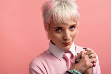 Kısa saçlı ve şık aksesuarlı güzel bir kadın neşeli bir şekilde gülümsüyor..