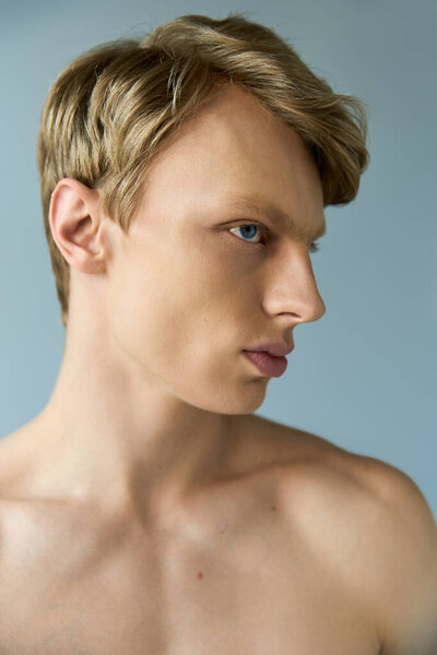 A young, alluring man with modern masculinity showcases his handsome profile in soft lighting.