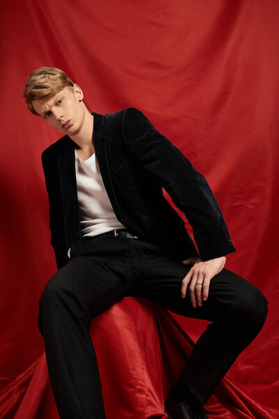 A young and alluring man poses confidently in a stylish outfit, showcasing modern masculinity.