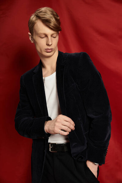 Модный молодой человек демонстрирует уверенность и очарование в индивидуальном наряде на смелом фоне.