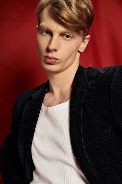 A young, handsome man exudes modern masculinity against a vibrant red backdrop.