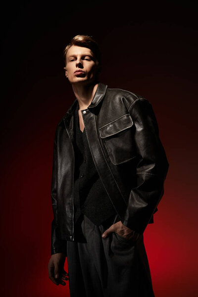Young man stands confidently in a sleek leather jacket against a vibrant, dramatic background.