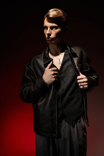 Молодой человек стильно позирует на ярком красном фоне, воплощая современную мужественность.