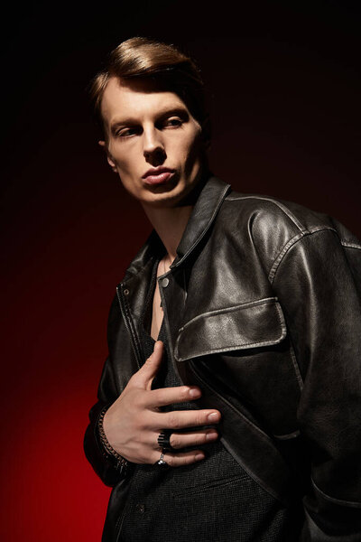 A young, alluring man stands confidently against a dark backdrop, exuding modern masculinity.