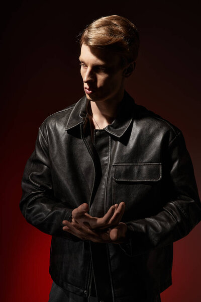 A young, handsome man embodies modern masculinity in low light with a vibrant backdrop.