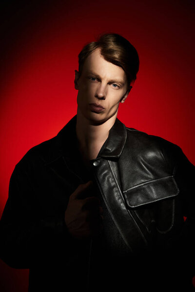 A young man showcases modern masculinity with confidence, set against a bold red backdrop.