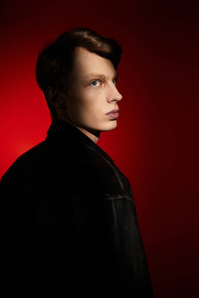 A handsome young man stands confidently in dramatic red light, embodying modern masculinity.