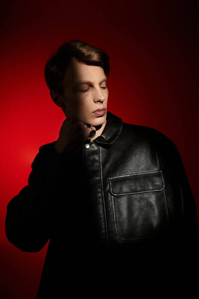 A handsome young man poses confidently against a vibrant red backdrop, embodying modern masculinity.