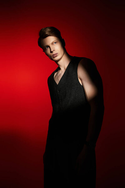 A young, appealing man stands confidently, embodying modern masculinity in bold red light.